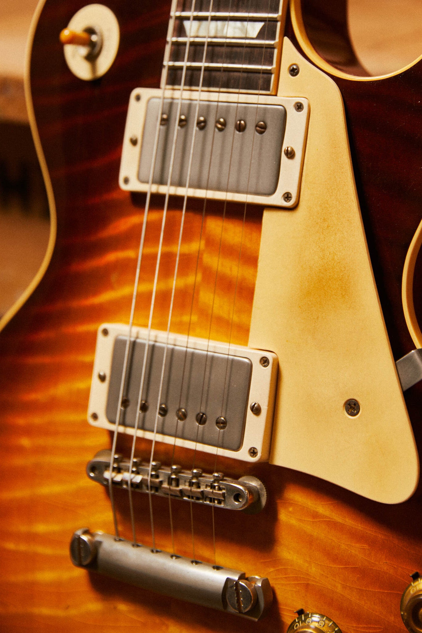 Close-up of a Les Paul electric guitar with a sunburst finish.